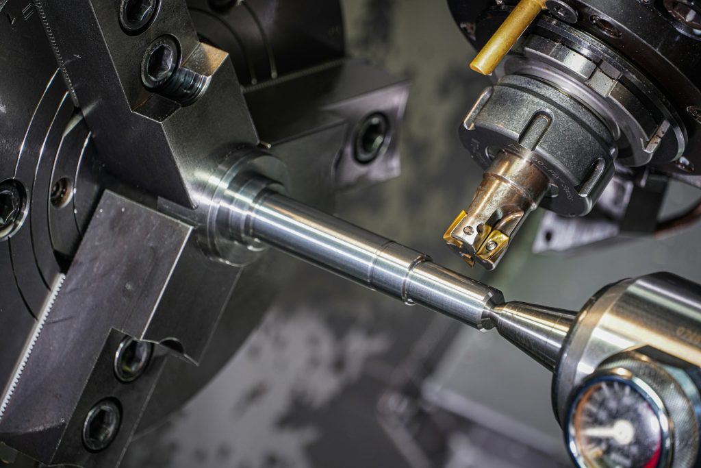 Metal lathe cutting a shiny metal rod with a sharp tool.