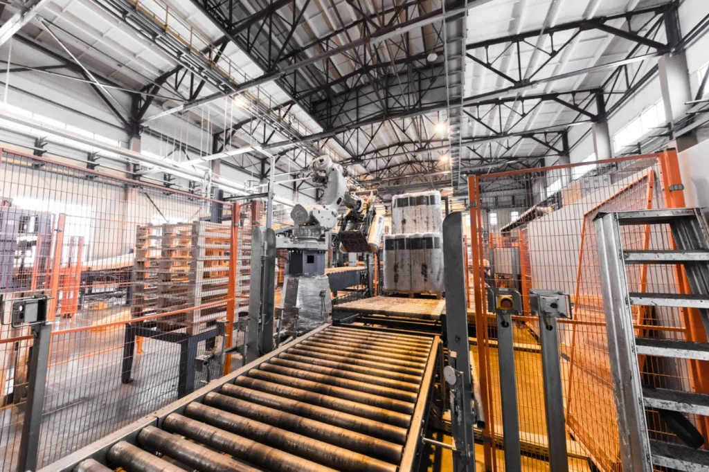 Automated robotic arm and roller conveyor system for industrial belting and packaging in a modern manufacturing facility.